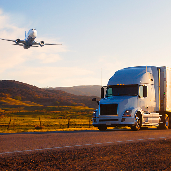 emerging technologies image of a plane flying over a tractor trailer on the highway in the mountains at sunset