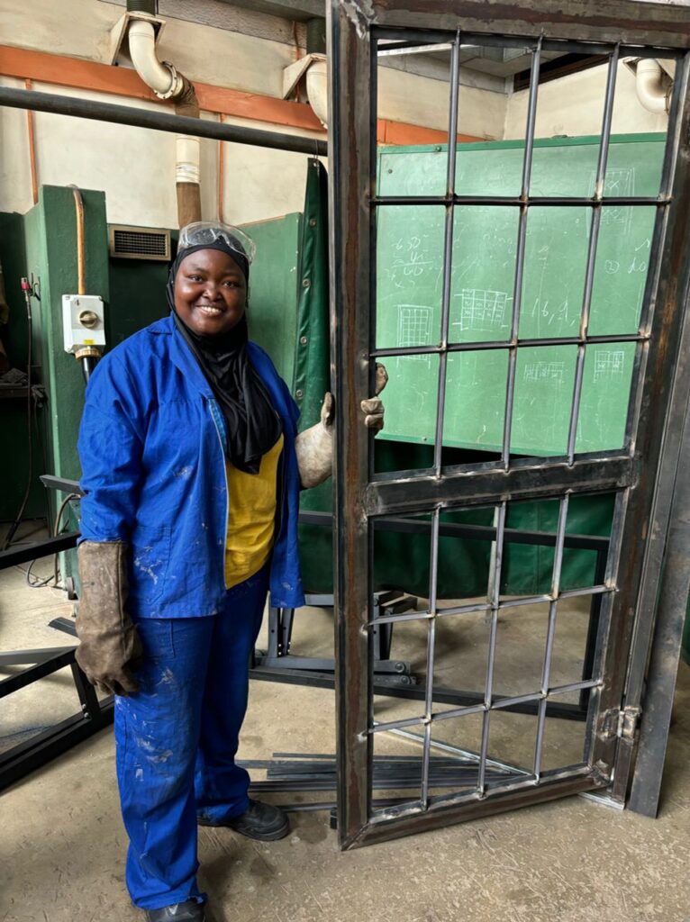 A woman in factory attire standing next to a newly built door.