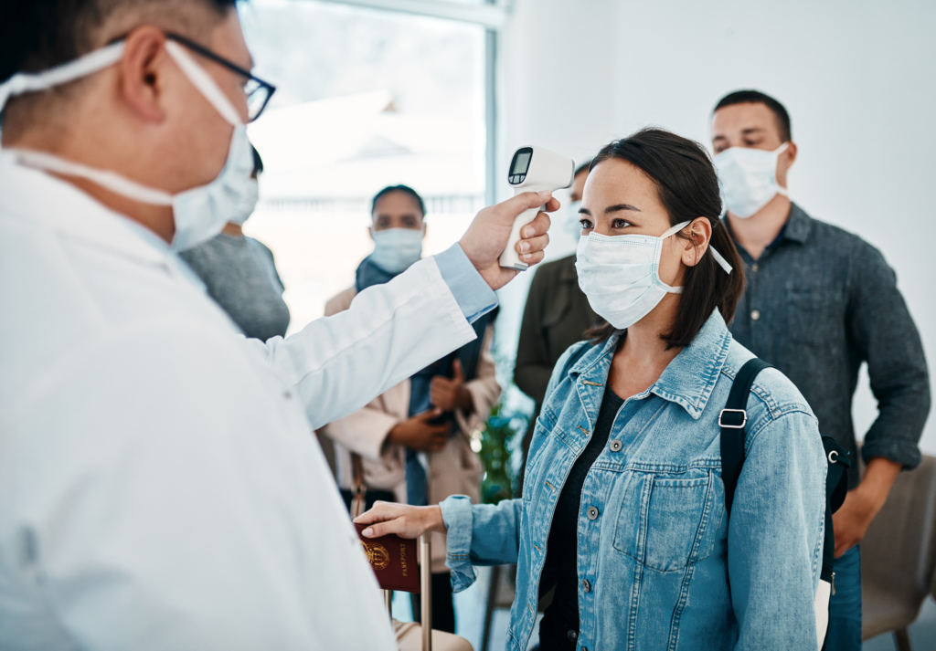 Woman in airport wearing mask getting temperature scan from official