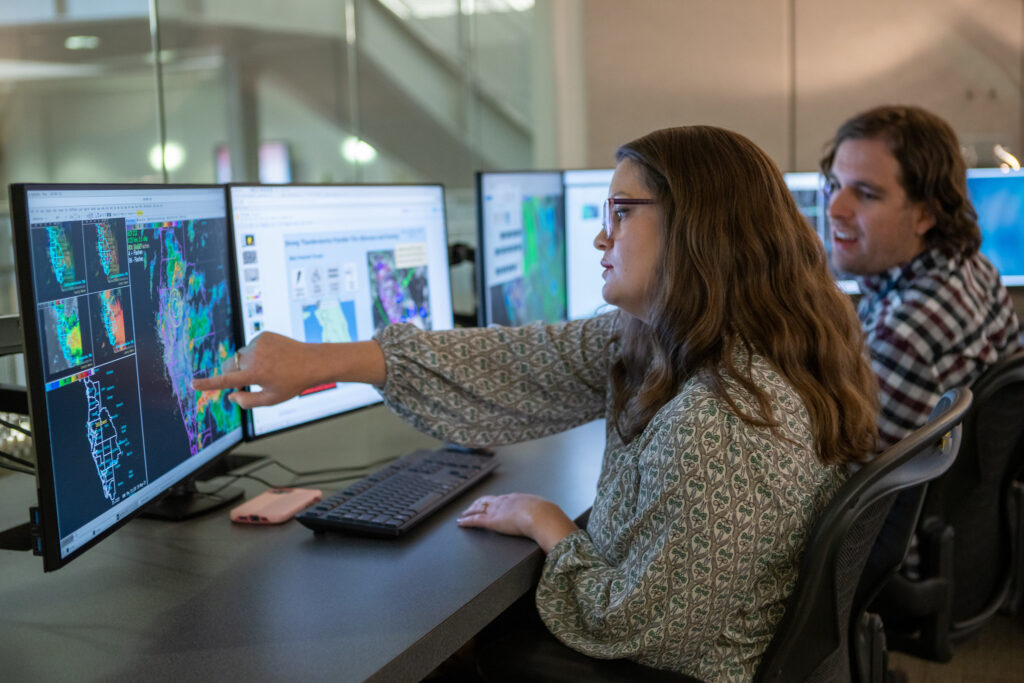 Two people at a desk reviewing climate information on a computer.